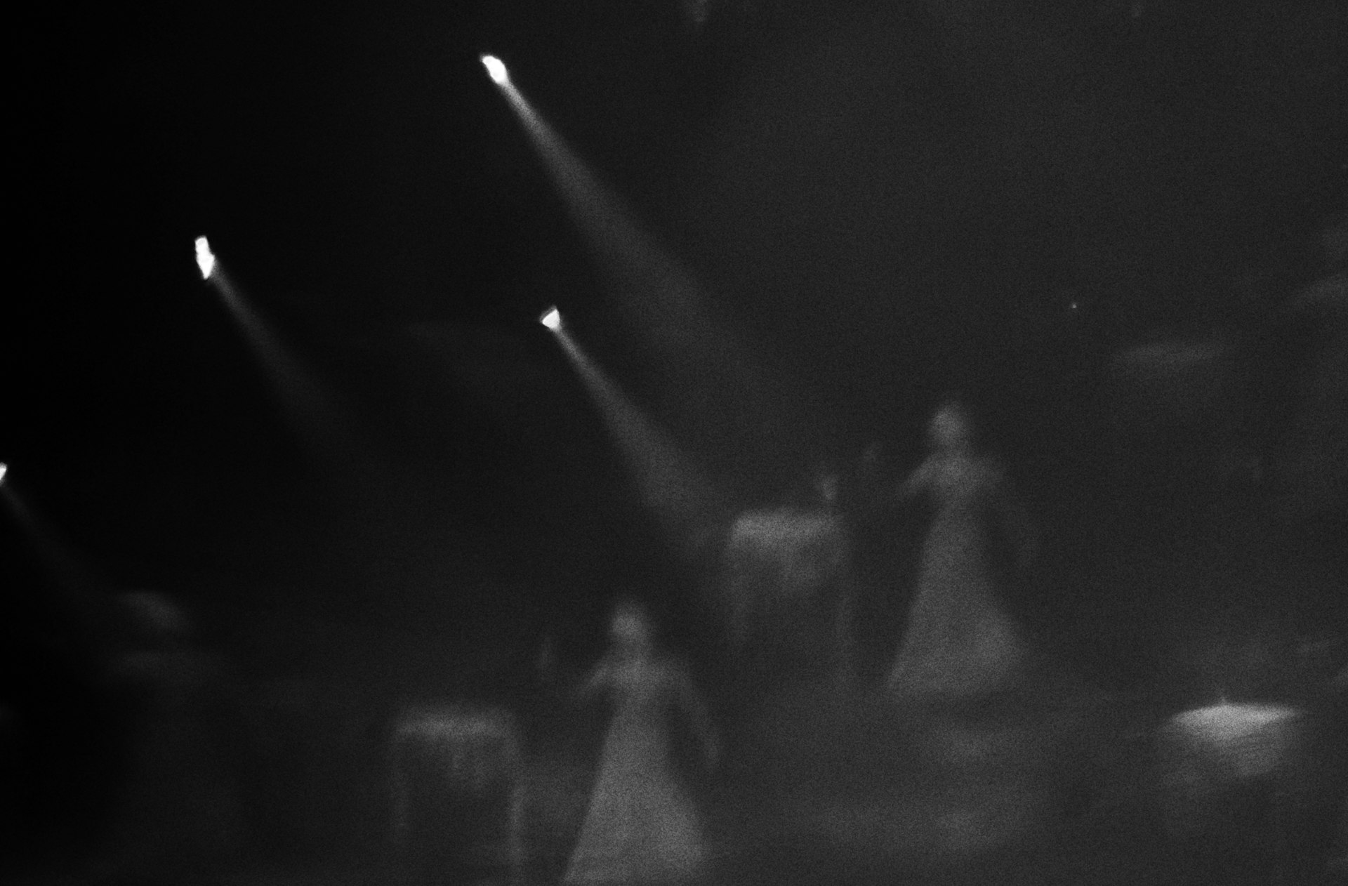 Performers on a dark theatre stage lit by bright spotlights